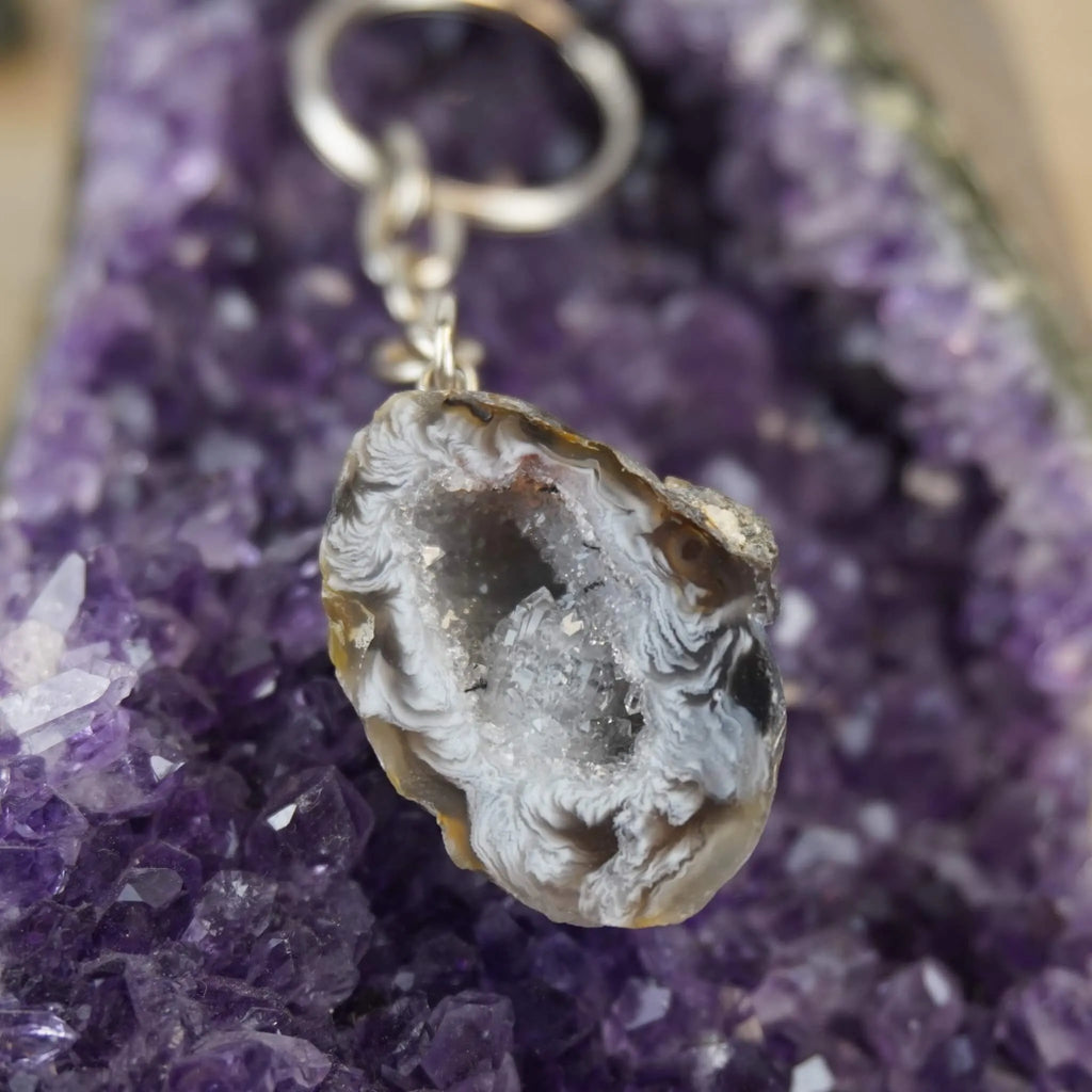 Achat Geode Schlüsselanhänger präsentiert auf violetter Amethyst-Druse