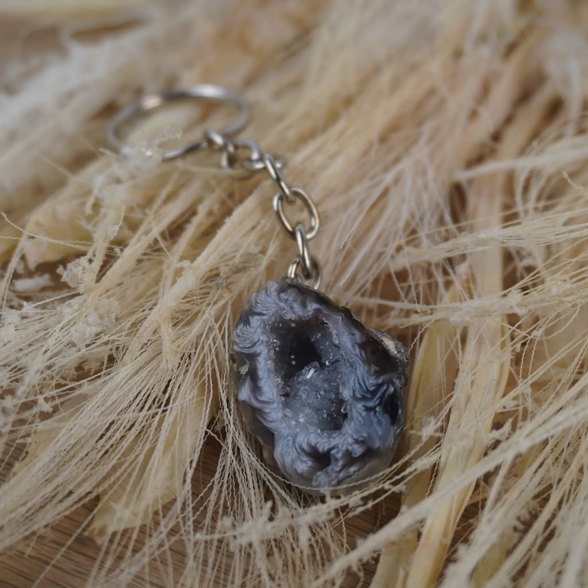 Achat Geode Schlüsselanhänger präsentiert auf hellen Naturfasern