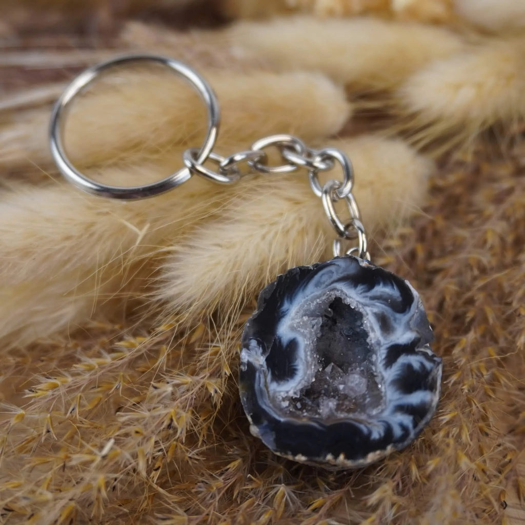 Achat Geode Schlüsselanhänger auf beigen flauschigen Trockenpflanzen arrangiert
