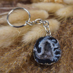 Achat Geode Schlüsselanhänger auf beigen flauschigen Trockenpflanzen arrangiert