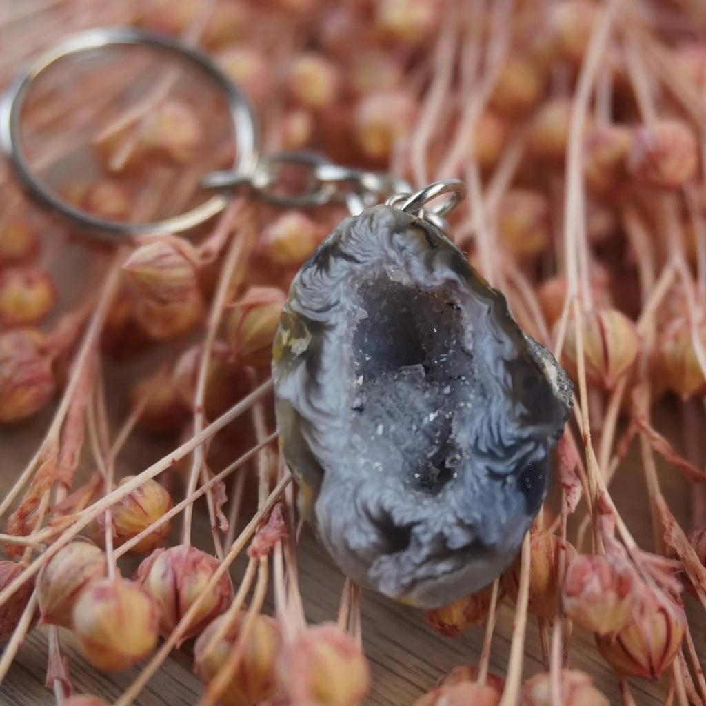 Achat Geode Schlüsselanhänger dekoriert auf rosa getrockneten Gräsern