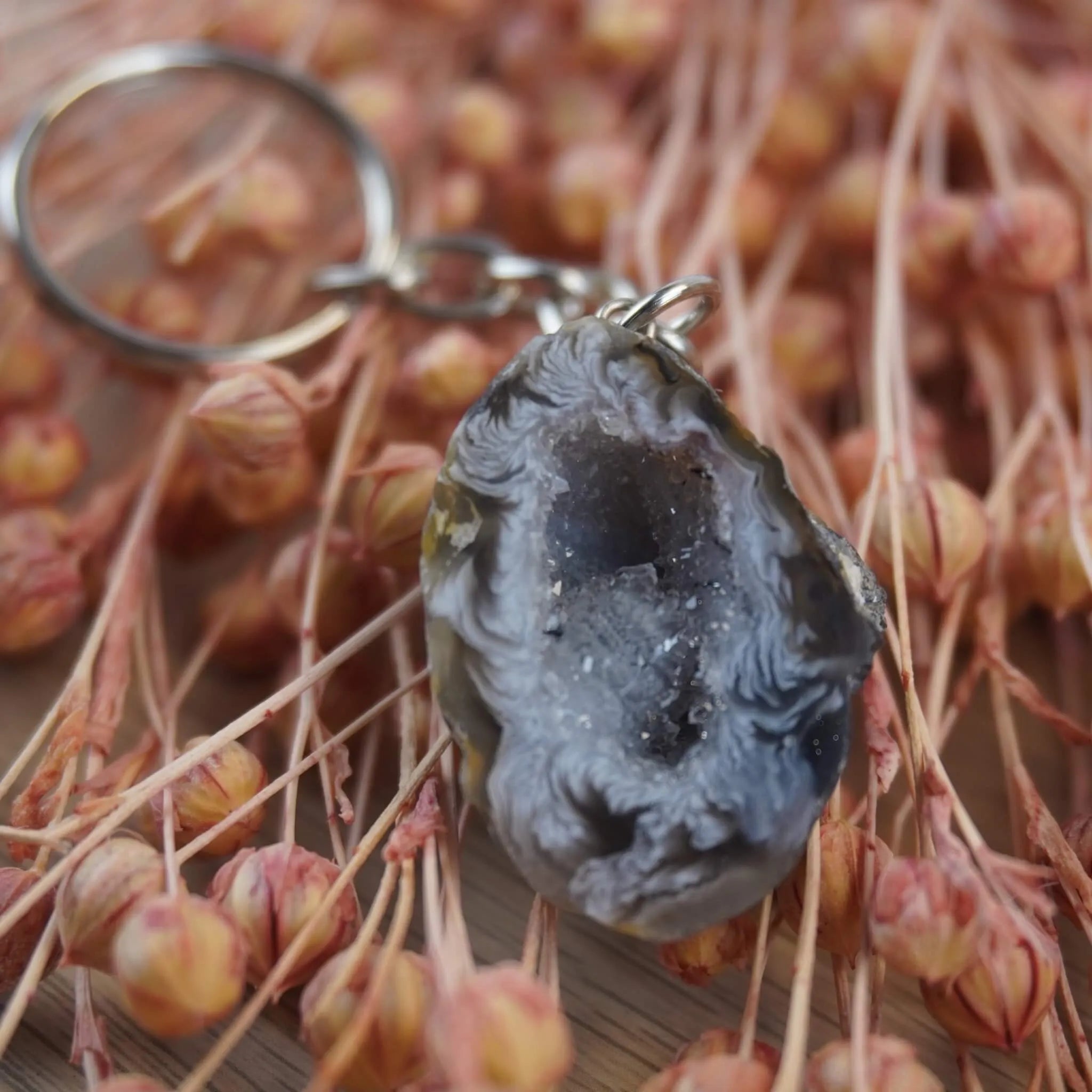 Achat Geode Schlüsselanhänger dekoriert auf rosa getrockneten Gräsern