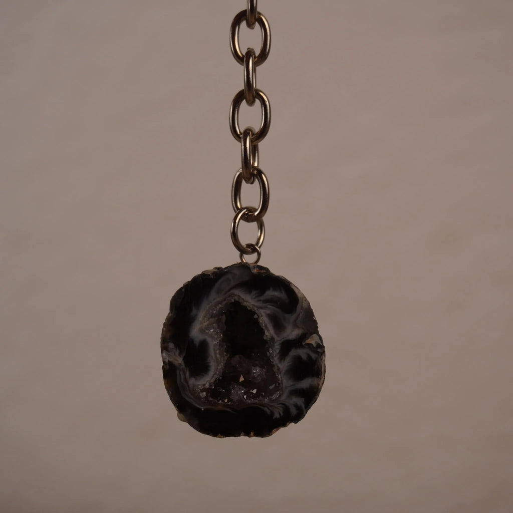Achat Geode Schlüsselanhänger frei hängend vor neutralem Hintergrund