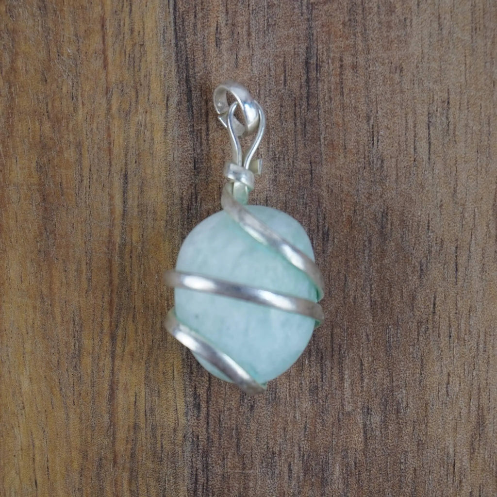 Amazonit Kettenanhänger mit Spiralfassung auf rustikalem Holzuntergrund