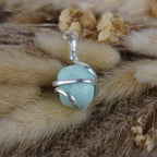 Amazonit Kettenanhänger mit silberner Spiralfassung auf beigen Trockenpflanzen