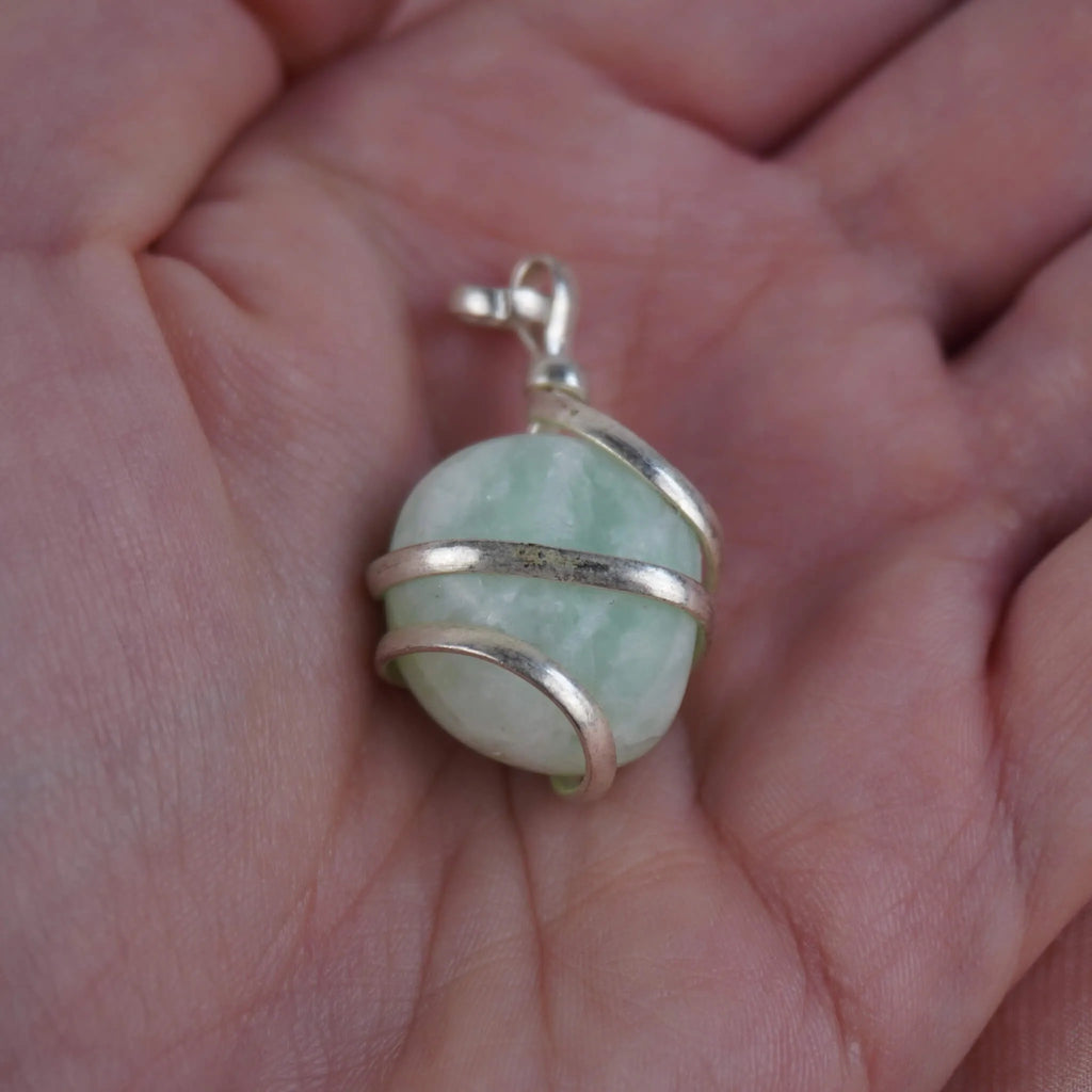 Amazonit Kettenanhänger mit silberner Spiralfassung in einer Hand liegend