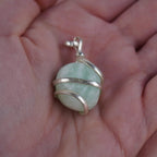Amazonit Kettenanhänger mit silberner Spiralfassung in einer Hand liegend