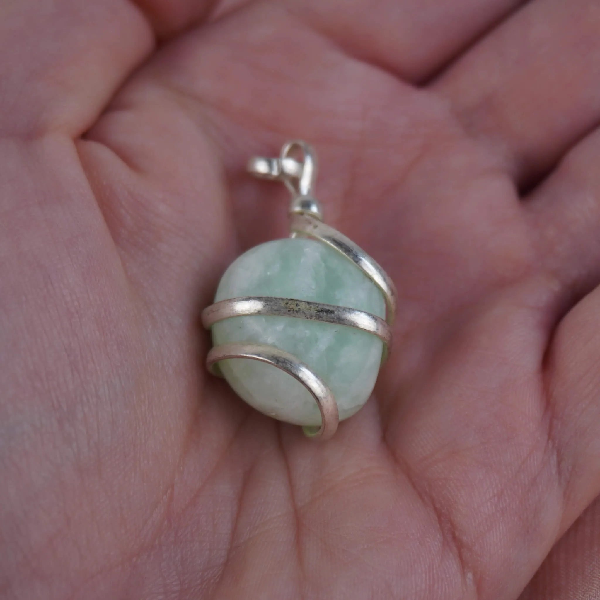 Amazonit Kettenanhänger mit silberner Spiralfassung in einer Hand liegend