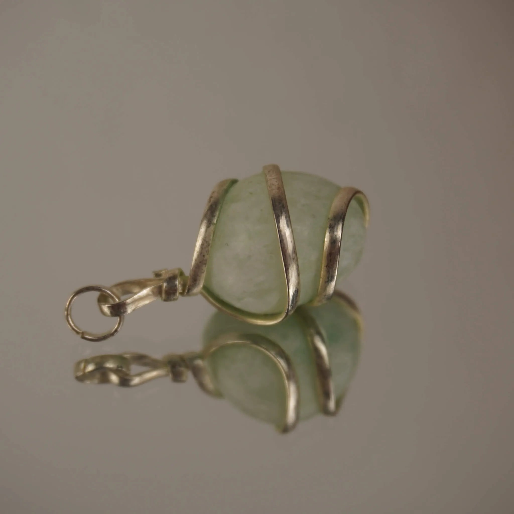 Amazonit Kettenanhänger mit silberfarbener Spiralfassung und Spiegelung auf glatter Fläche