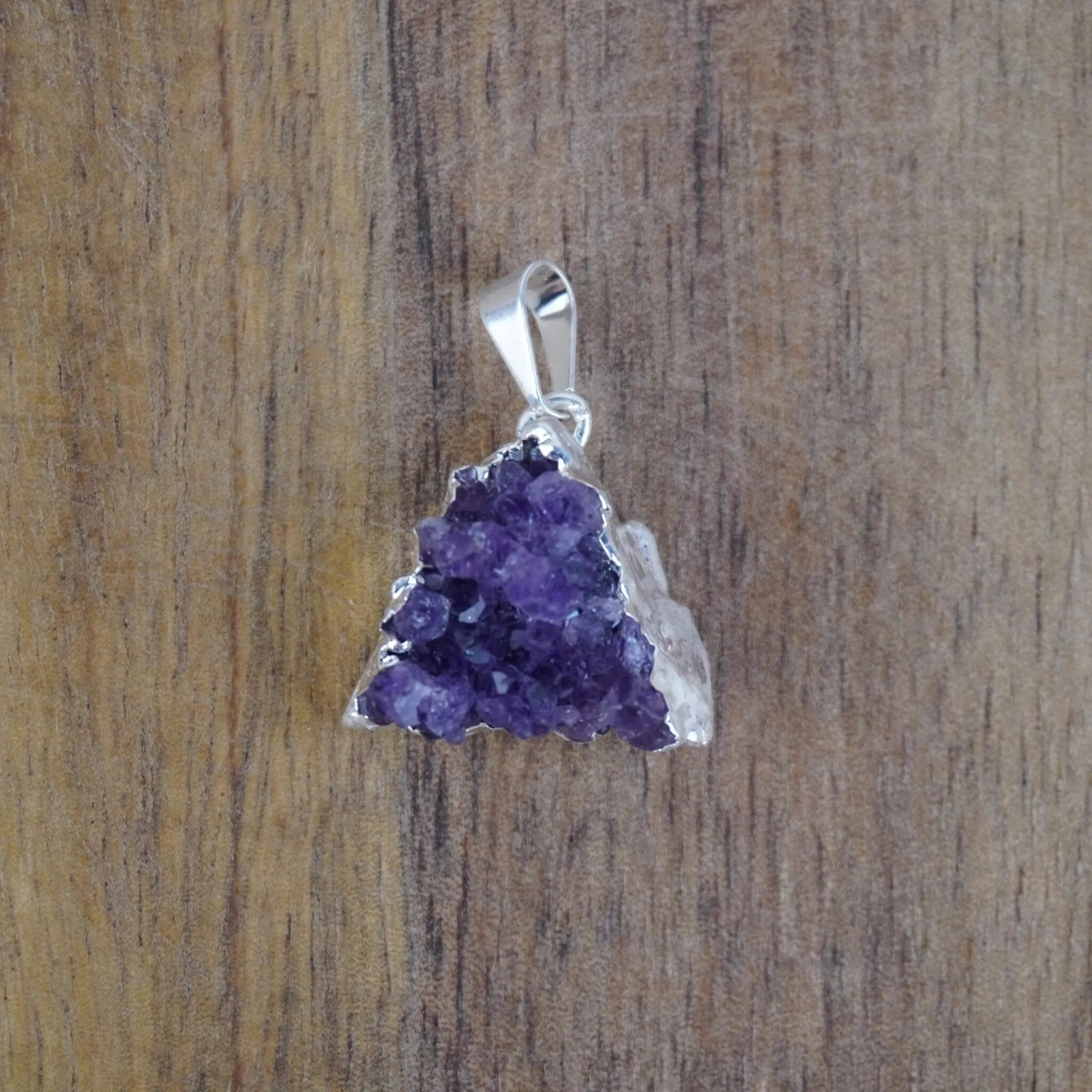 Amethyst Druse Kettenanhänger mit Silberfassung vor Holzuntergrund