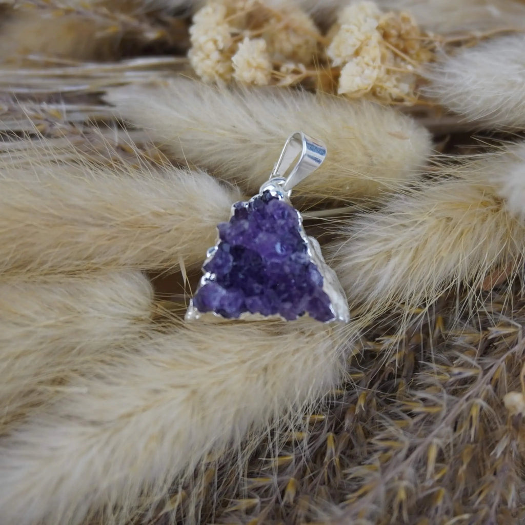 Amethyst Druse Kettenanhänger mit Silberfassung dekoriert auf beigen Trockenpflanzen