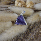 Amethyst Druse Kettenanhänger mit Silberfassung dekoriert auf beigen Trockenpflanzen