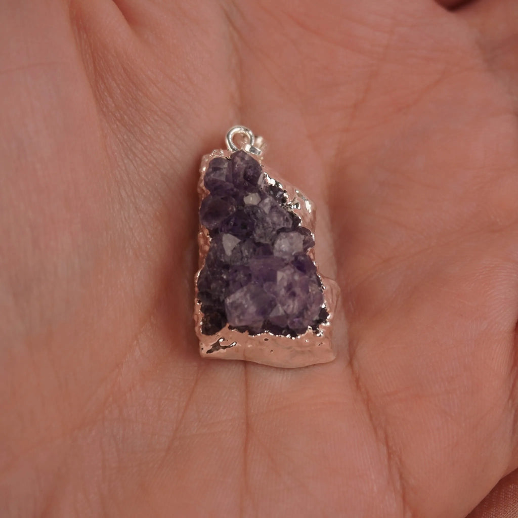 Amethyst Druse Kettenanhänger mit silberner Umrandung in einer Hand liegend