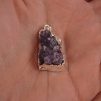 Amethyst Druse Kettenanhänger mit silberner Umrandung in einer Hand liegend