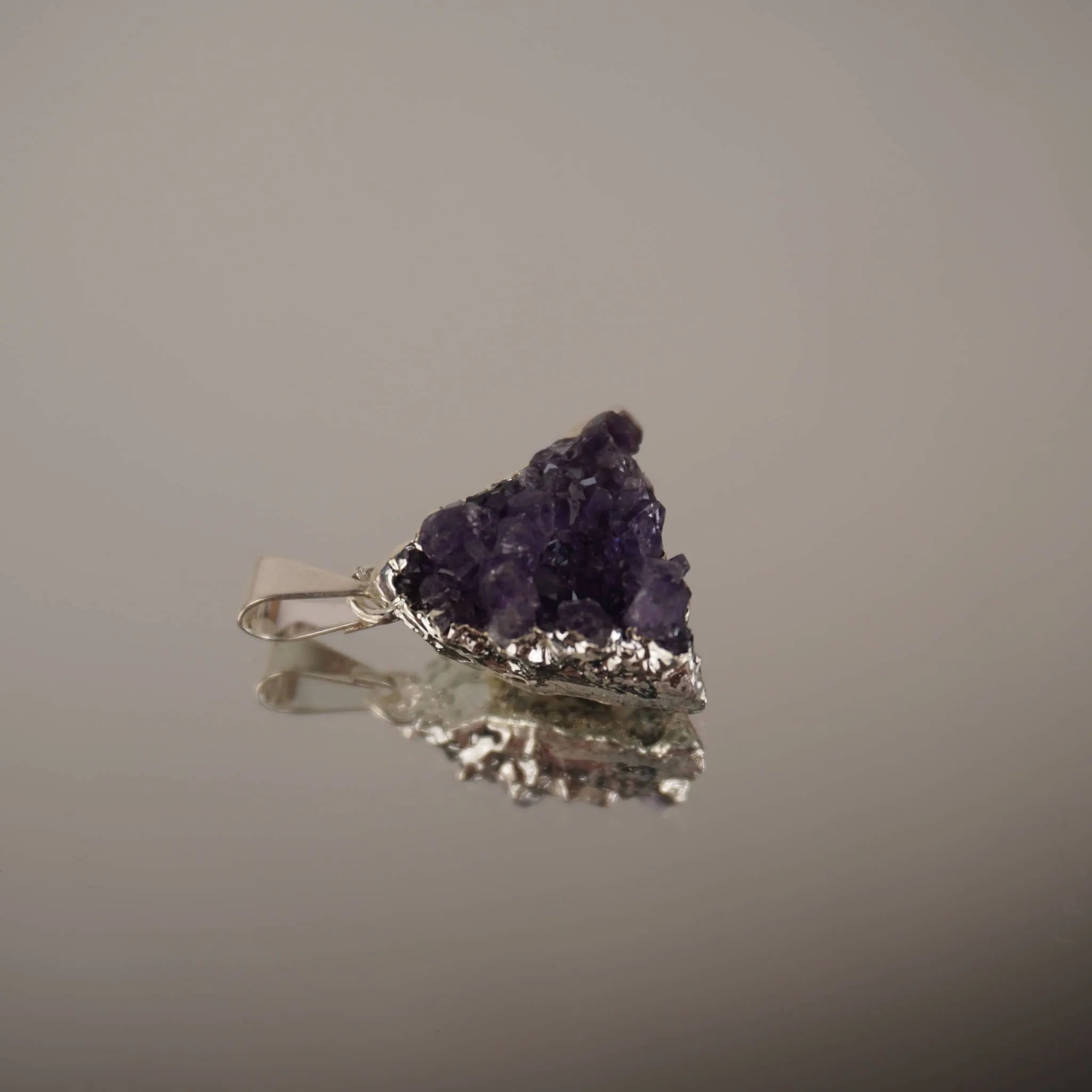 Liegender Amethyst Drusen Kettenanhänger mit Silberfassung und Spiegelung auf glänzender Fläche