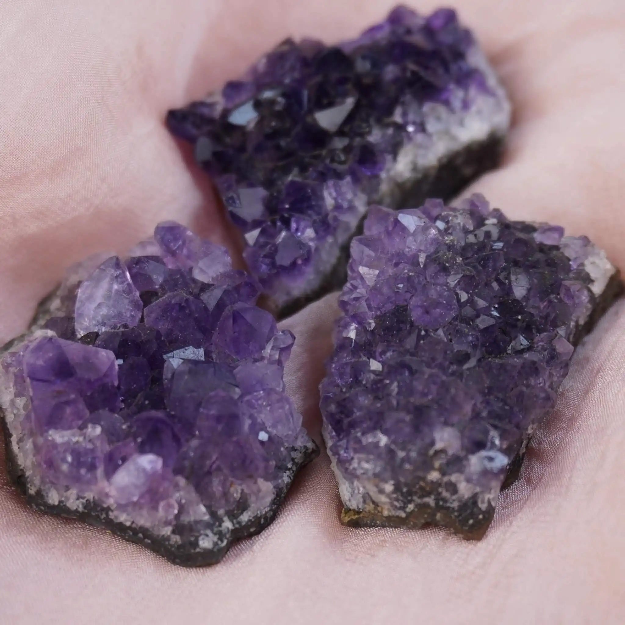 Drei Amethystdrusen auf rosa Stoff