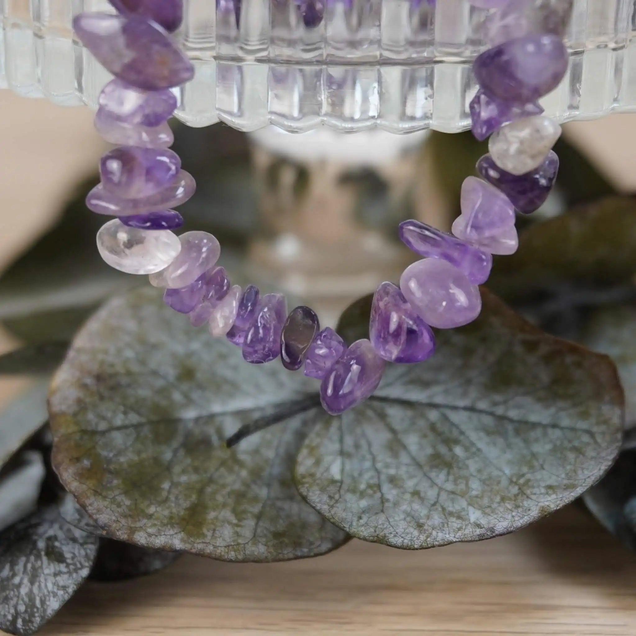 Amethyst Halskette mit Splittersteinen auf grünen Blättern und Glasgefäß inszeniert
