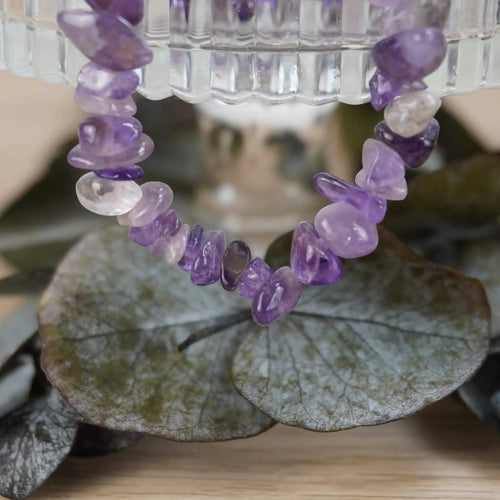 Amethyst Halskette mit Splittersteinen auf grünen Blättern und Glasgefäß inszeniert