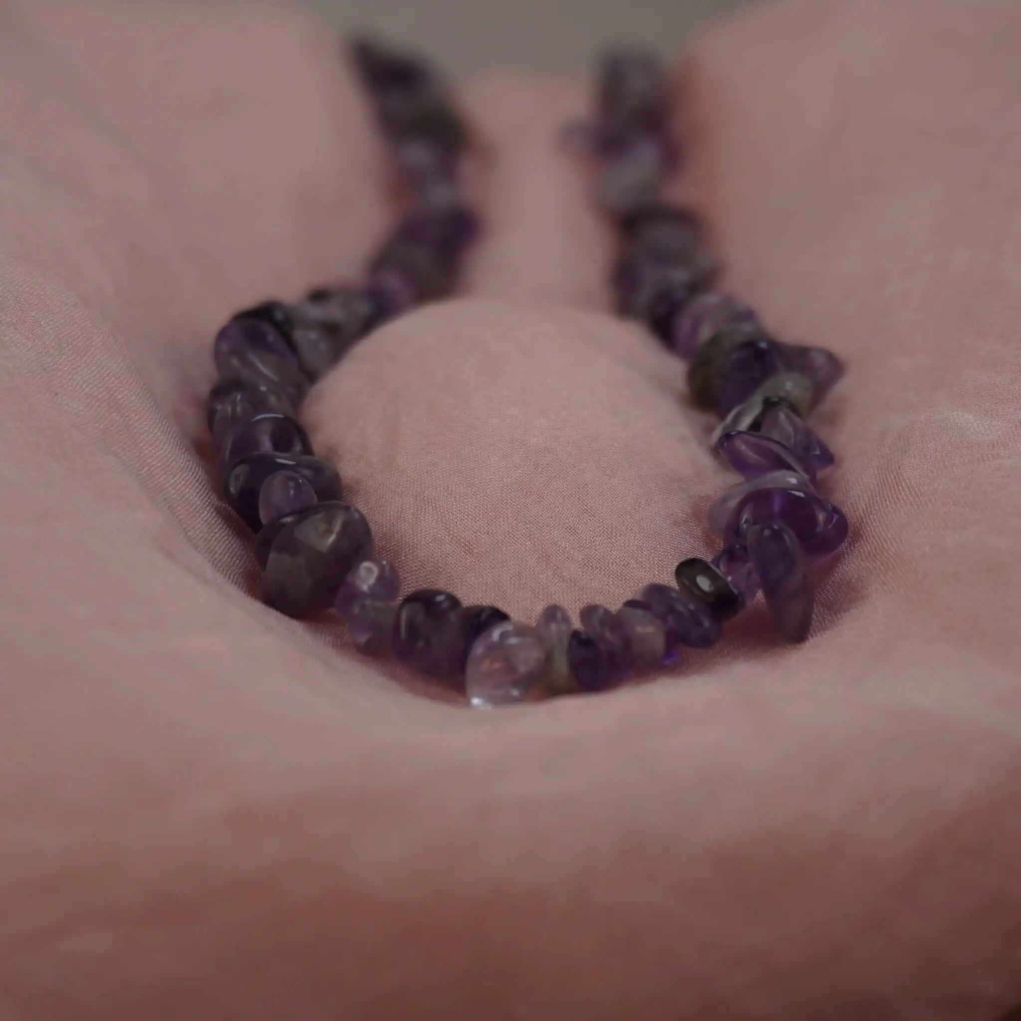 Amethyst Halskette mit Splittersteinen, dekorativ auf rosa Stoffpolster präsentiert