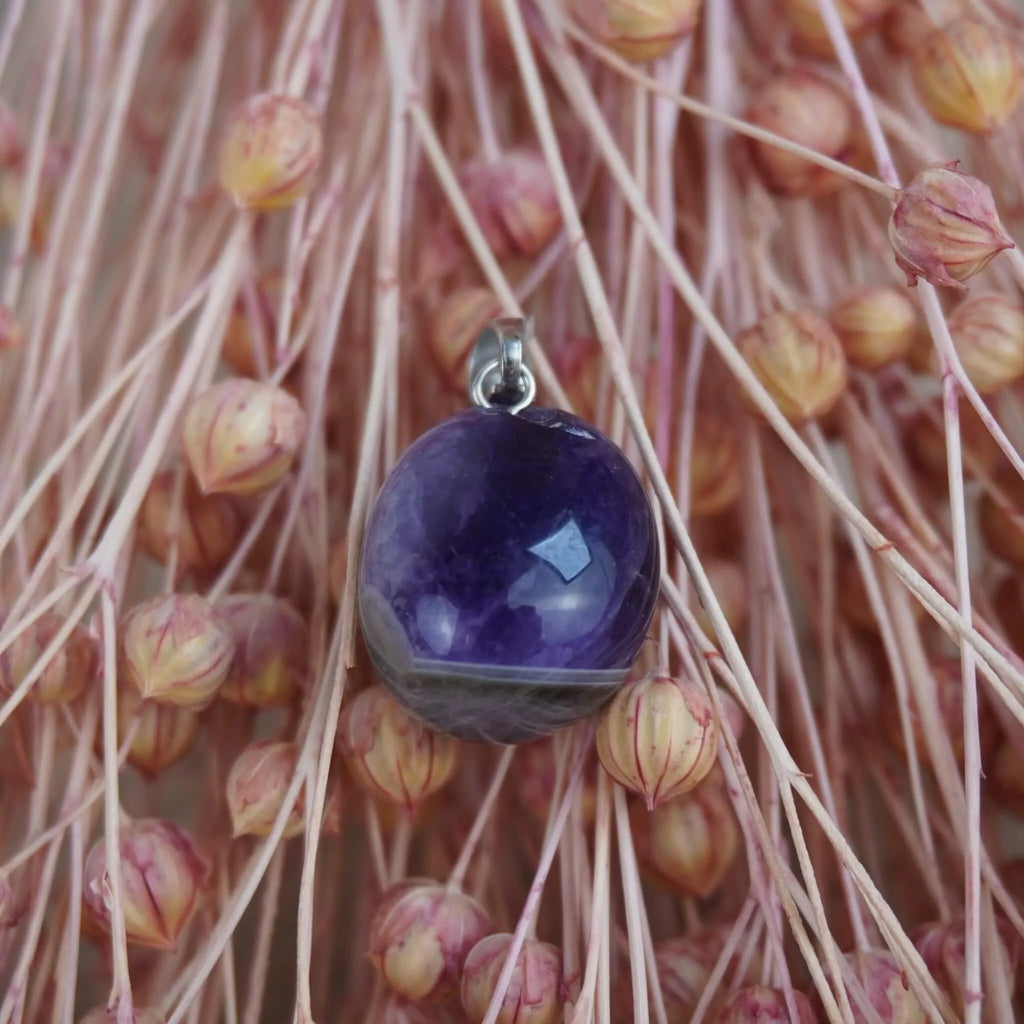 Amethyst Kettenanhänger mit Silber Öse arrangiert vor rosa Trockenblumen