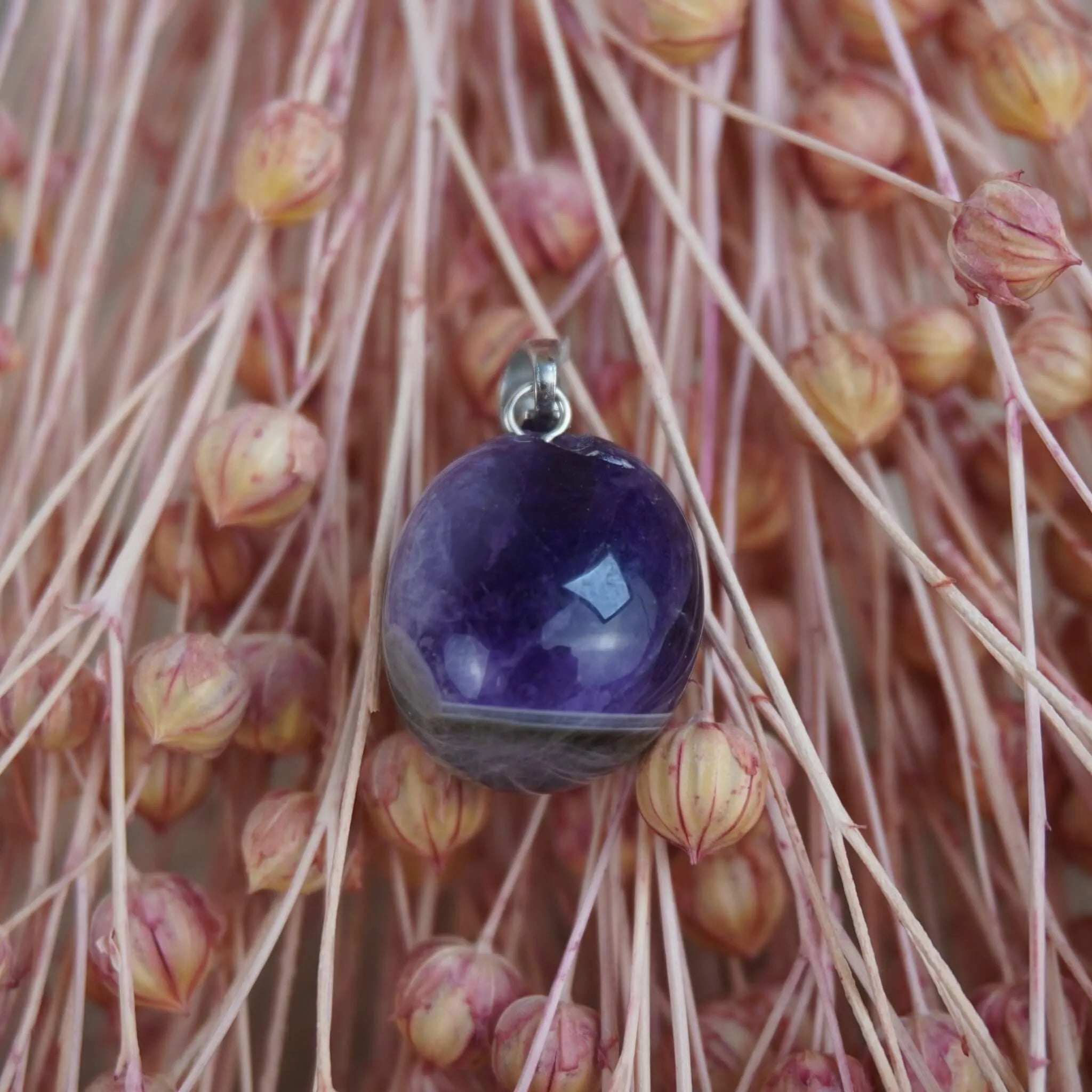 Amethyst Kettenanhänger mit Silber Öse arrangiert vor rosa Trockenblumen