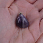 Amethyst Kettenanhänger mit silberfarbener Öse in einer Hand liegend