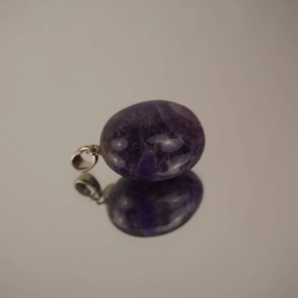 Amethyst Trommelstein Kettenanhänger mit silberfarbener Öse und Spiegelung auf glänzender Fläche