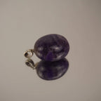 Amethyst Trommelstein Kettenanhänger mit silberfarbener Öse und Spiegelung auf glänzender Fläche