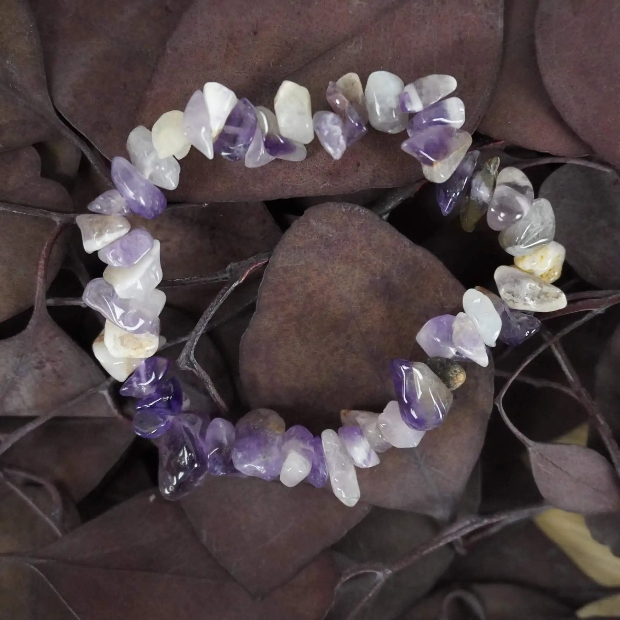 Amethyst Splitterarmband aus violetten Edelstein-Splittern auf dunklen Blättern platziert