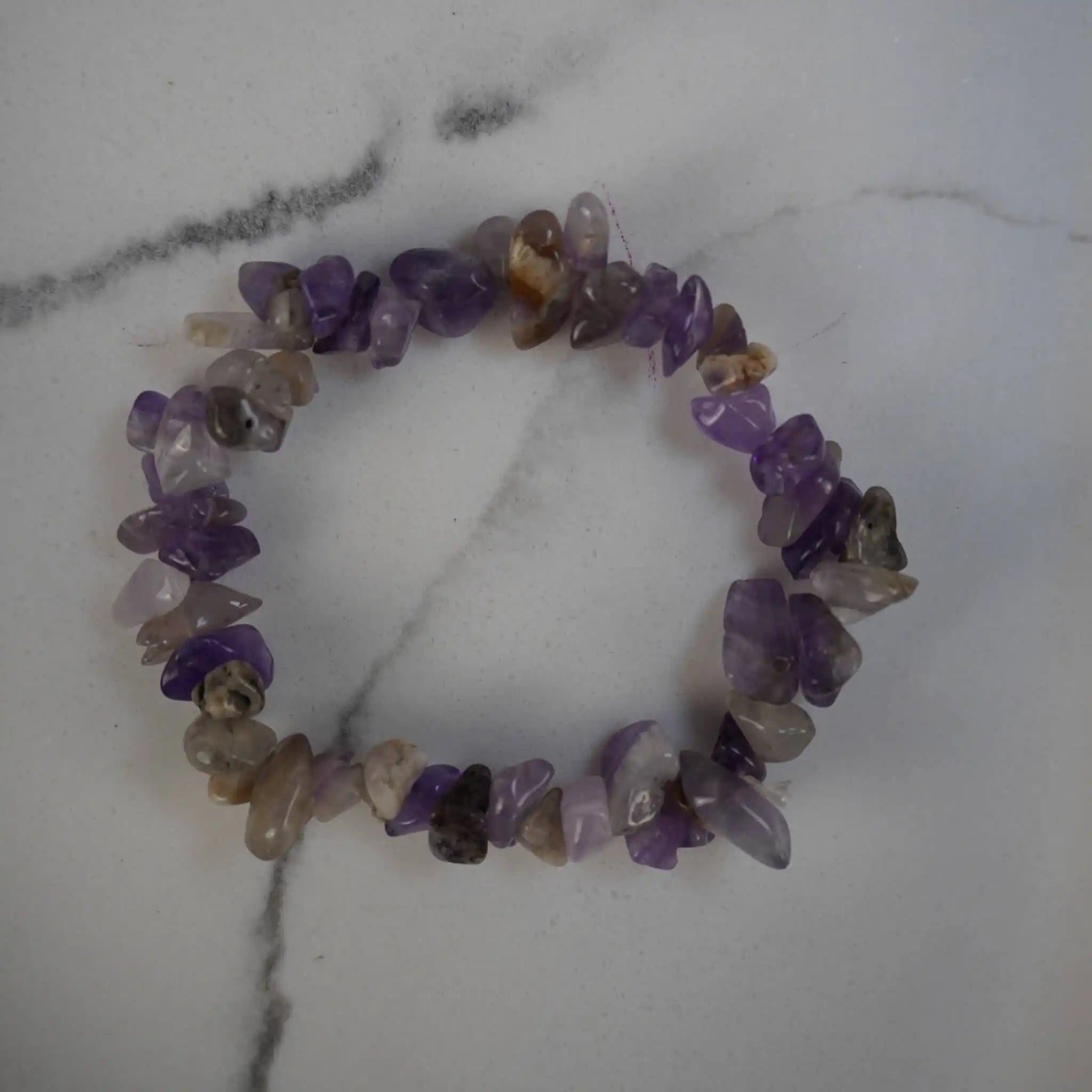 Amethyst Splitterarmband mit violetten Natursteinen auf weißer Marmorfläche