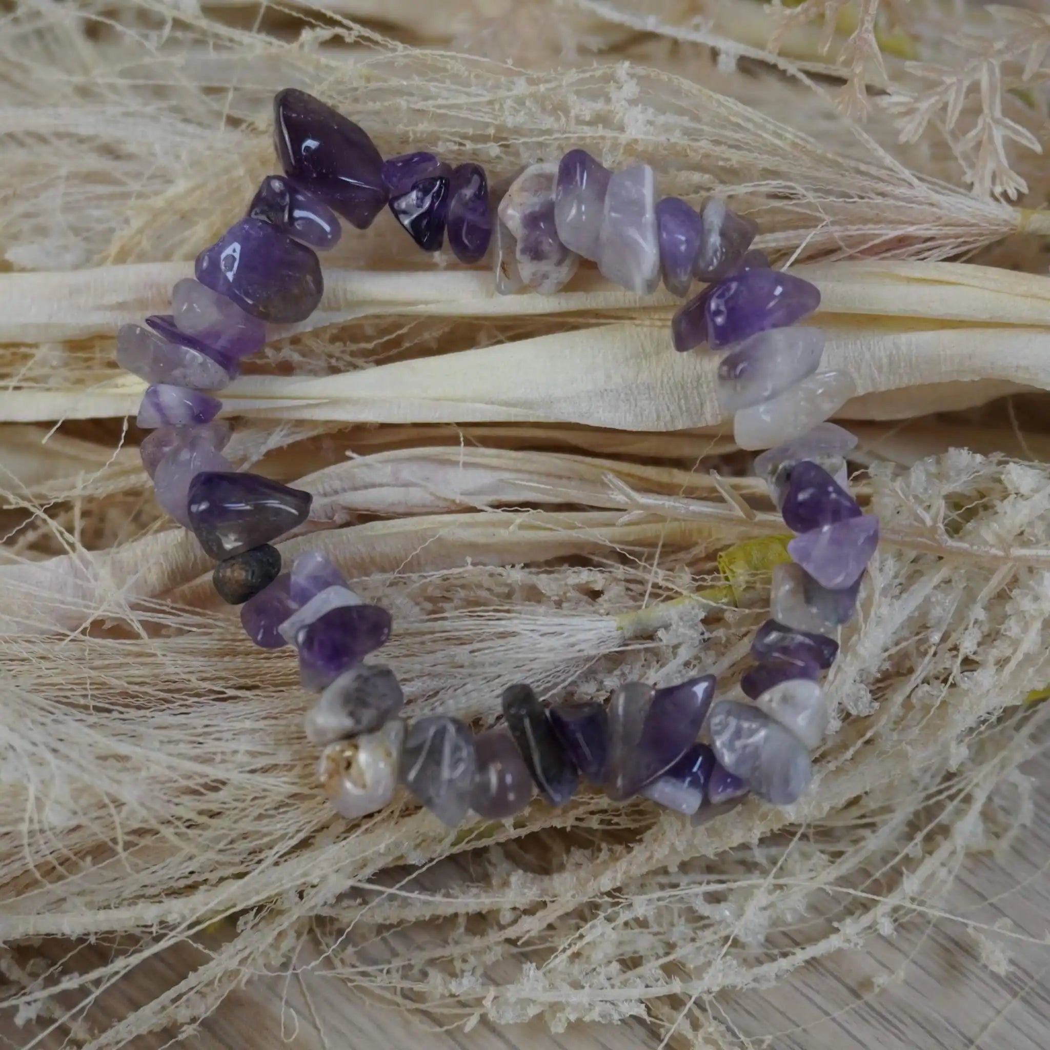 Lila Amethyst Splitterarmband auf hellem Trockenblumen fotografiert