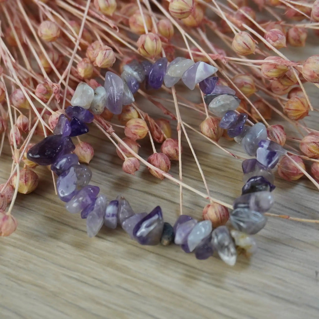 Amethyst Splitterarmband dekorativ auf rosafarbenen Trockenblumen arrangiert