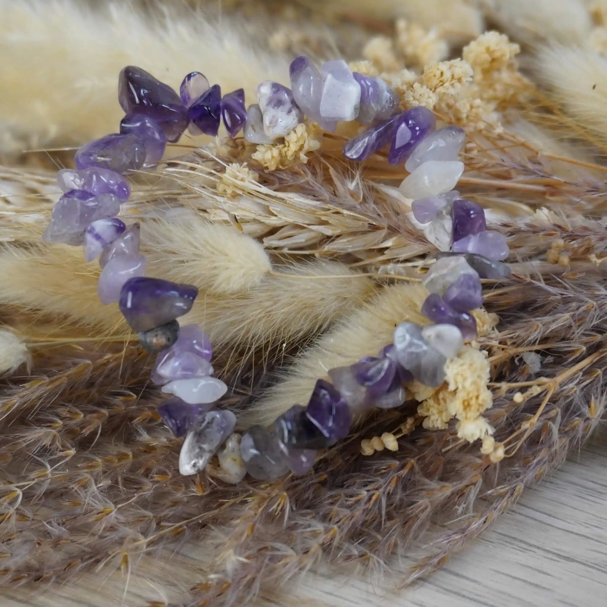 Amethyst Splitterarmband dekorativ auf getrockneten Pflanzen und Gräsern inszeniert