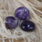 Amethyst Trommelsteine auf hellem Naturfaser-Hintergrund