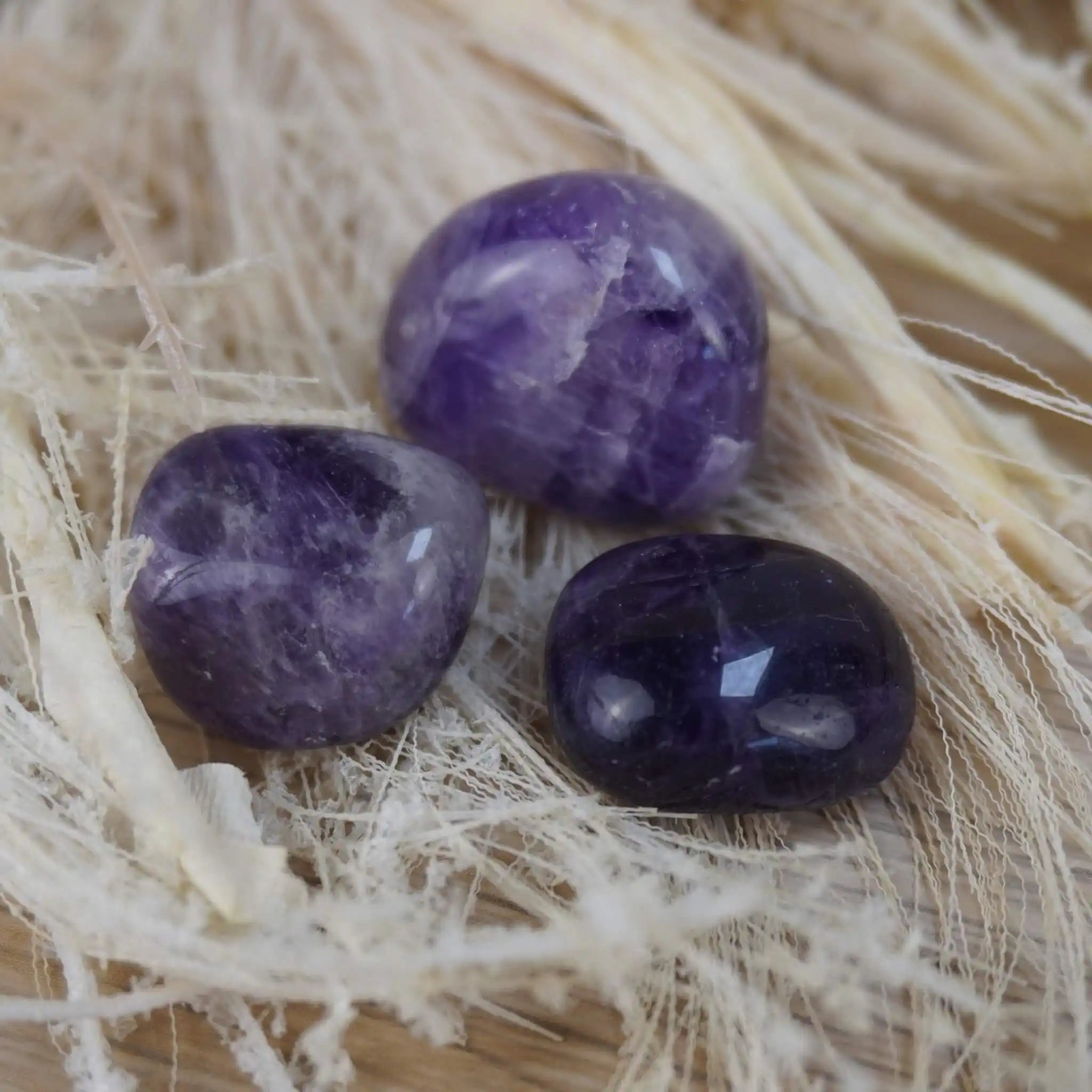 Amethyst Trommelsteine auf hellem Naturfaser-Hintergrund