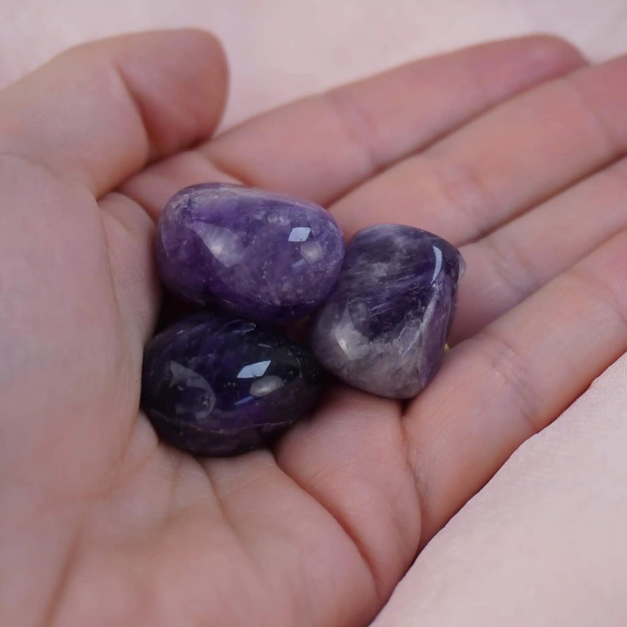 Drei Amethyst Trommelsteine in einer Hand gehalten