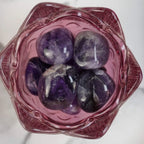 Mehrere Amethyst Trommelsteine in einer rosa Glasschale