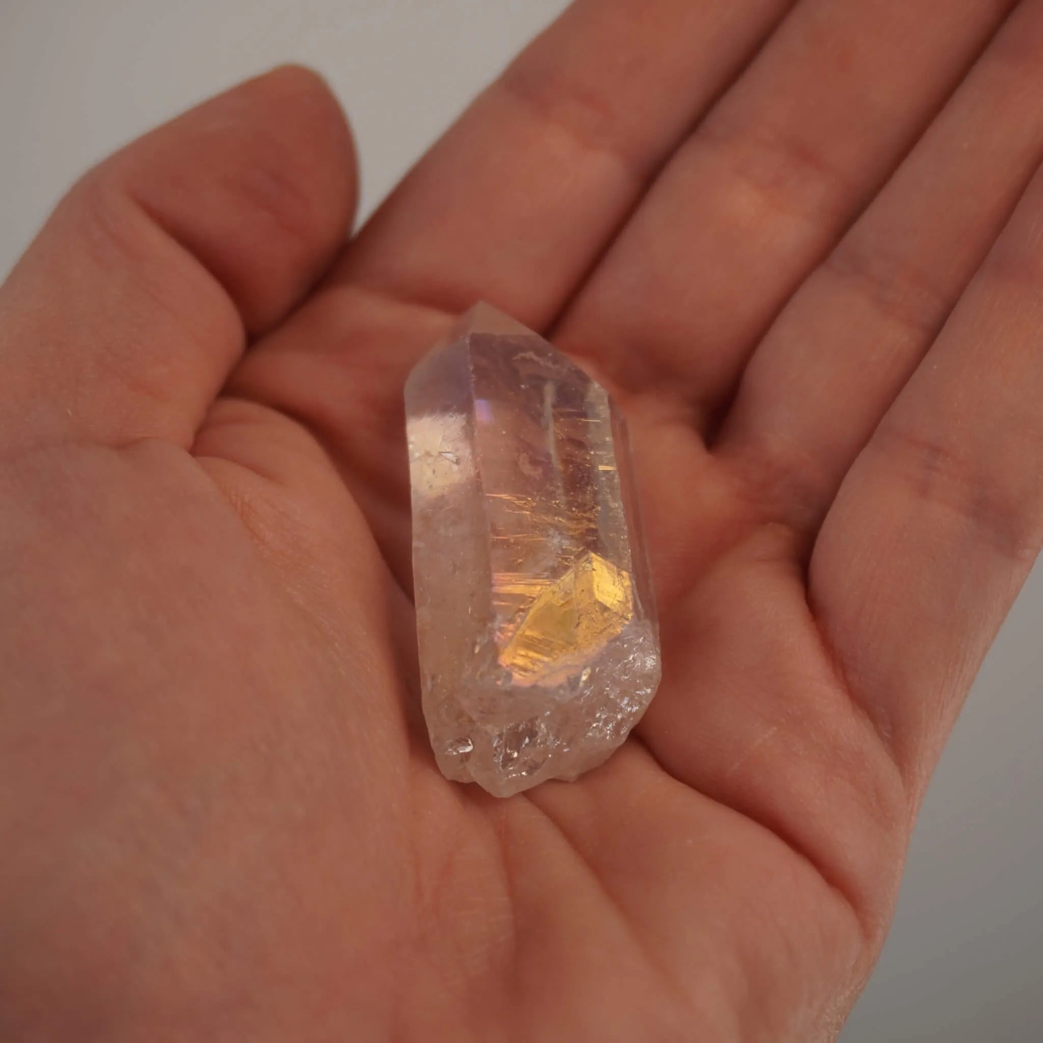 Angel Aura Bergkristall Spitze in der Hand gehalten mit irisierendem Glanz