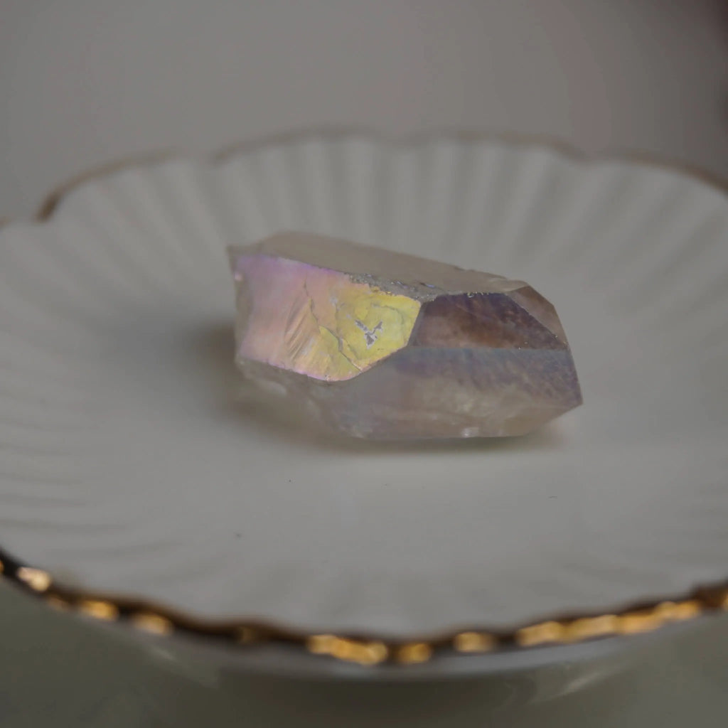 Angel Aura Bergkristall Spitze auf weißem Teller mit Goldrand schimmernd präsentiert