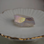 Angel Aura Bergkristall Spitze auf weißem Teller mit Goldrand schimmernd präsentiert