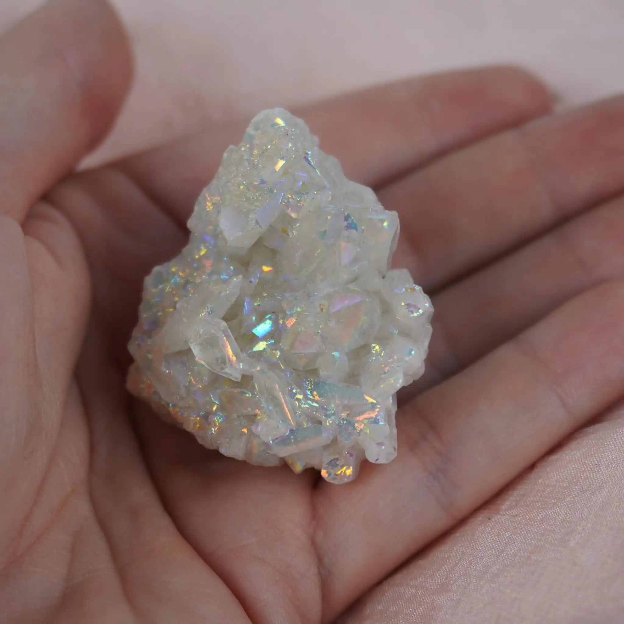 Angel Aura Cluster Kristall mit irisierendem Schimmer in einer Hand gehalten