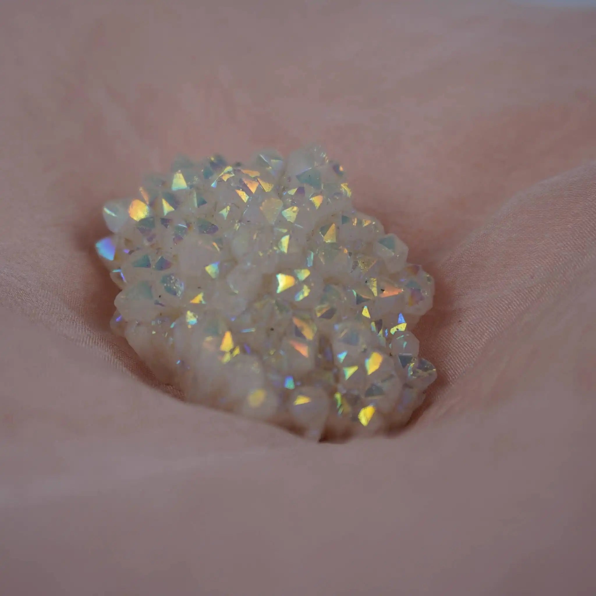 Angel Aura Cluster Kristall mit Regenbogenschimmer auf rosafarbenem Stoff
