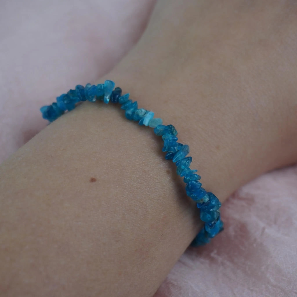 Apatit Splitterarmband am Handgelenk vor zartrosa Hintergrund