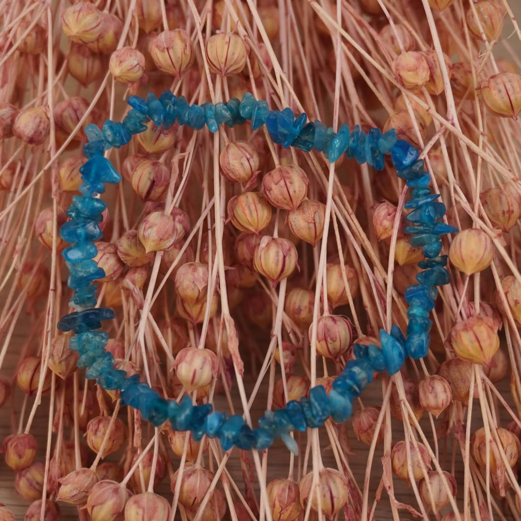 Apatit Splitterarmband vor rosafarbenen Trockenblumen, frischer Farbkontrast