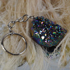 Aqua Aura Druse Schlüsselanhänger mit bunt schimmernden Kristallen auf hellen Naturfasern