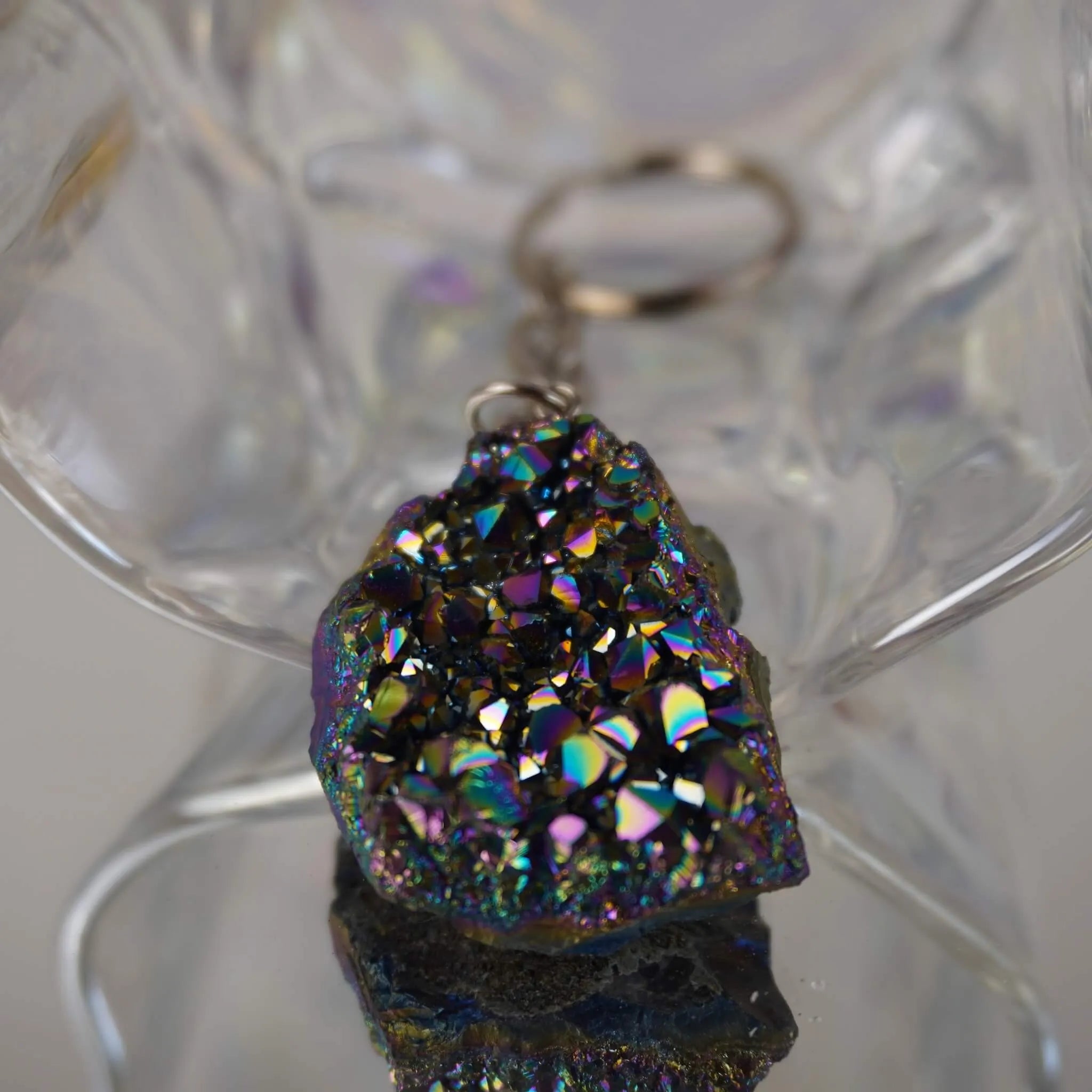 Aqua Aura Druse Schlüsselanhänger mit intensivem  Regenbogenschimmer vor transparenter Glasdeko