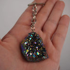 Titan Aqua Aura Druse Schlüsselanhänger mit Metallkette in einer Hand gehalten
