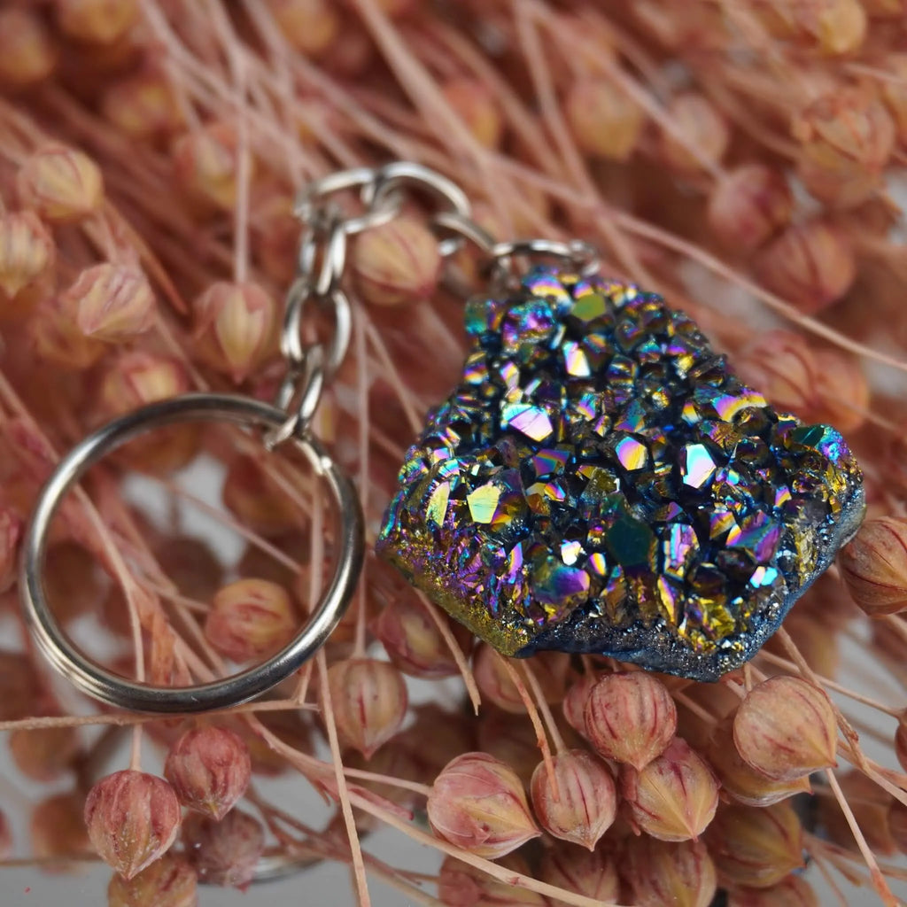 Aqua Aura Druse Schlüsselanhänger mit funkelnder Oberfläche arrangiert auf rosa Trockenblumen