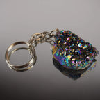 Aqua Aura Druse Schlüsselanhänger mit vielfarbig funkelnder Kristallfläche auf glänzender Fläche