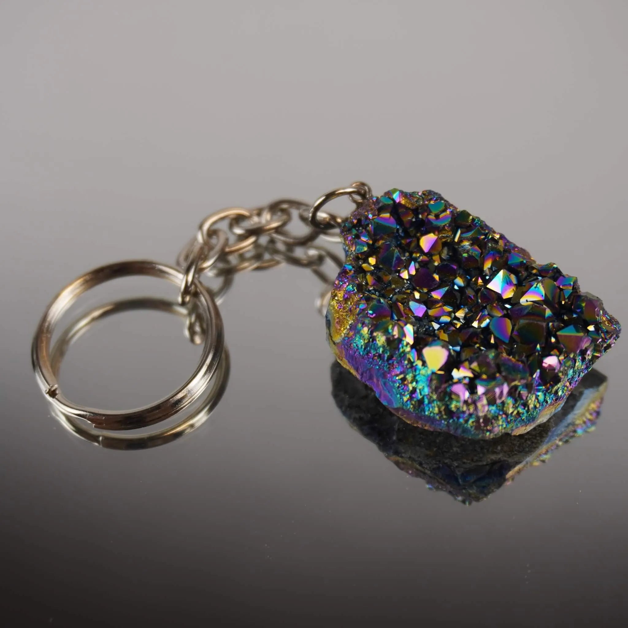 Aqua Aura Druse Schlüsselanhänger mit vielfarbig funkelnder Kristallfläche auf glänzender Fläche